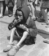 An emaciated child eats in the streets of the Warsaw ghetto. [LCID: 89469]Bir deri bir kemik kalmış çocuk Varşova gettosu caddelerinde bir şeyler yerken.